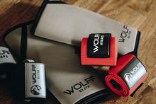red wrist wraps with knee sleeves and black wrist wraps laying on hardwood floor