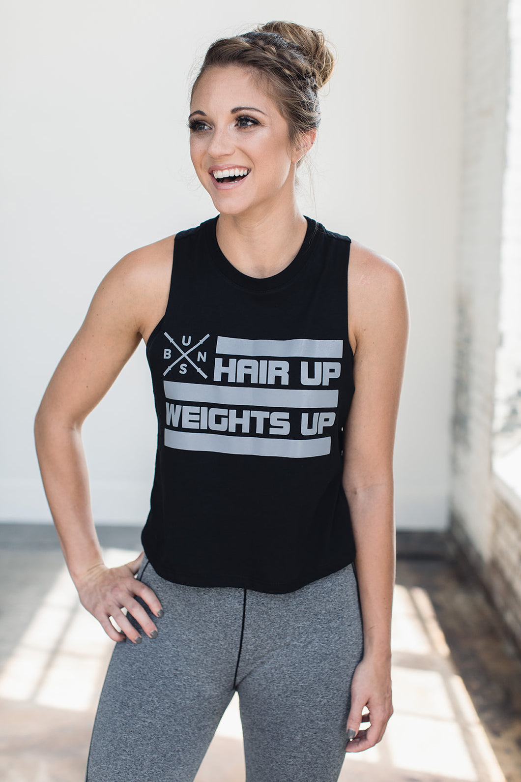 Woman laughing while wearing a graphic muscle crop tank 