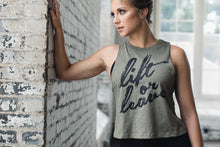 Athletic woman wearing an olive green crop tank saying "Lift or Leave"