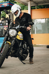 man riding a motorcycle wearing a charcoal henley with skull graphic design