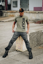 tattooed man sitting wearing a fitted olive graphic tee