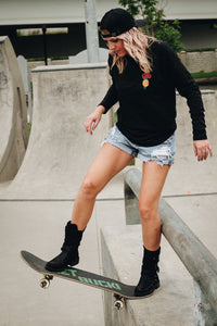 woman with blonde hair skateboarding wearing a charcoal long sleeve tee