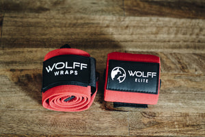 red wrist wraps with a wolf logo laying on a hardwood floor