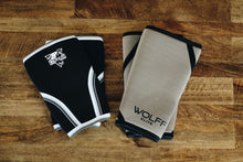 2 pairs of grey and black knee sleeves laying on a hardwood floor