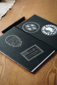 buns and barbells stickers on a black notebook on a wooden table