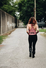 woman walking away wearing a mauve crop top tank and black jeans