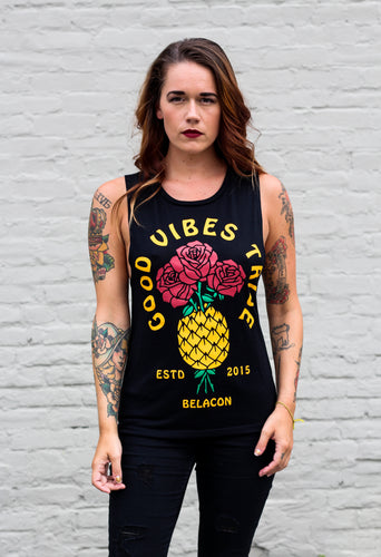 tattooed woman wearing a black tank top with a pineapple graphic design