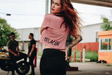 Woman walking away wearing a mauve crop top and black jeans